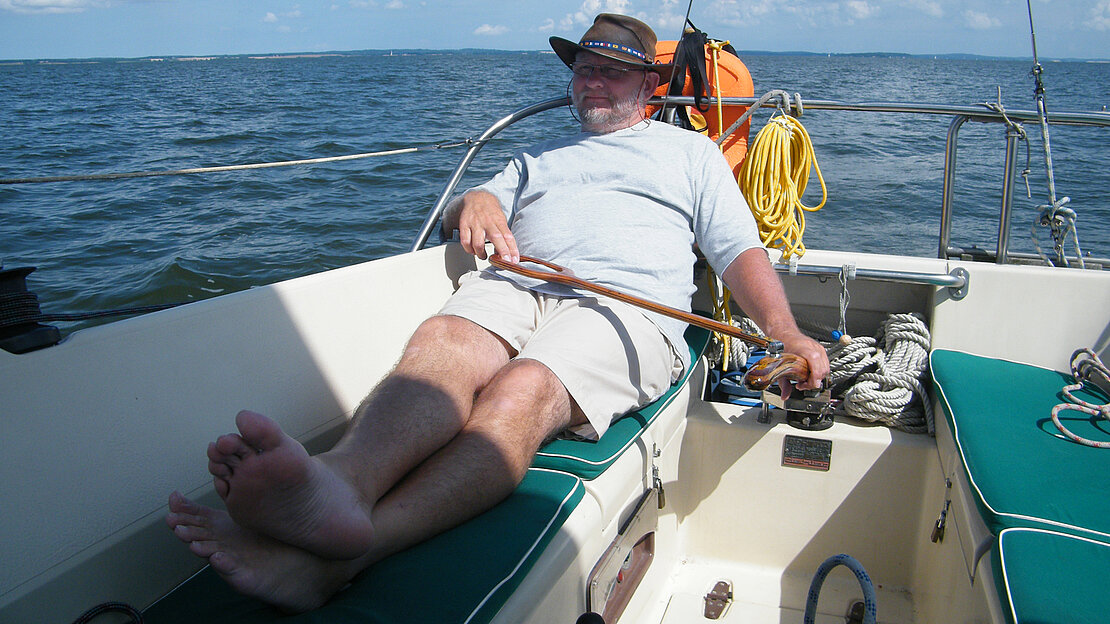 男士安详地坐在小船上，面带宁静的表情凝视远方。