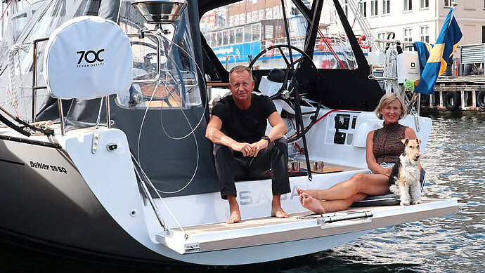 Owners of the Dehler sailing yacht Saga sit on their baiting platform in harbor accompanied by dog
