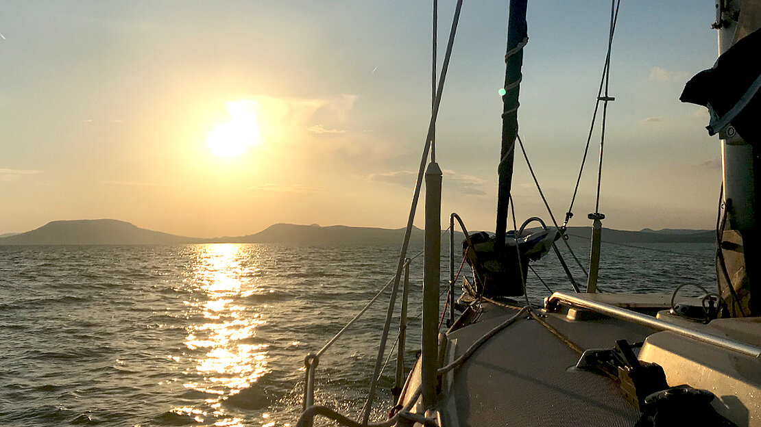 Bask in the opulence of a breathtaking sunset over the tranquil waters, as the Nati sailboat rests at anchor.