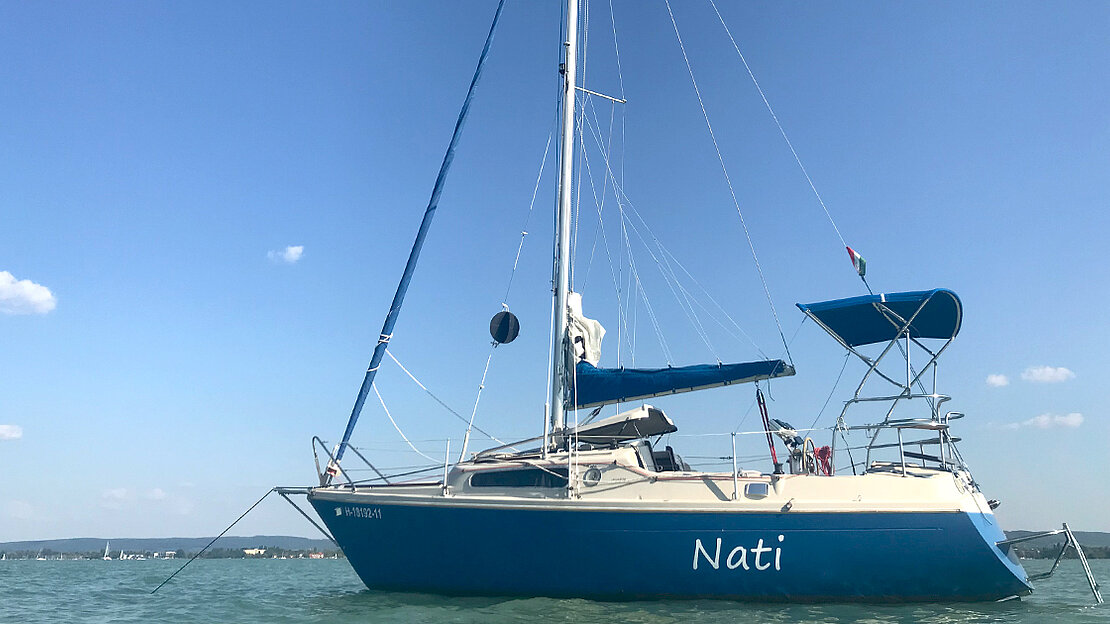 A magnificent blue sailboat named "Nadi" gracefully rests at anchor, exuding an aura of opulence and elegance on the tranquil waters.