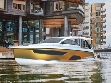 Sealine S430 cruises on a river alongside buildings