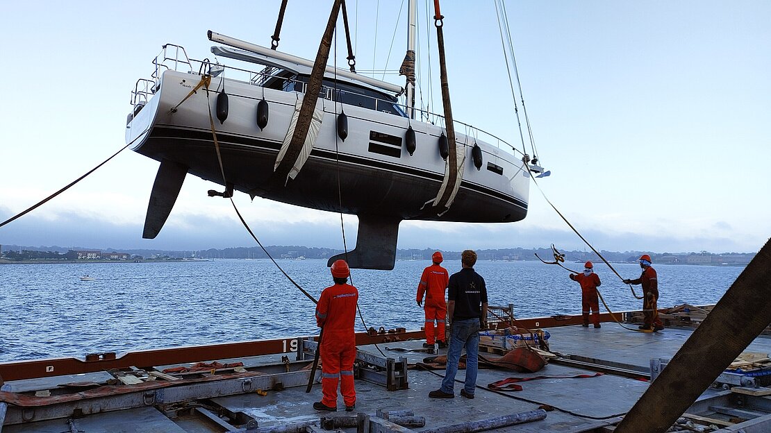 Yacht gets lifted by crane onto cargo ship deck