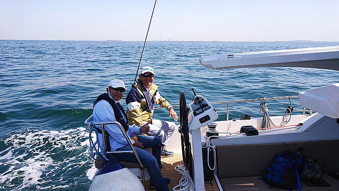Bluewater sailing friends at the wheel of their yacht
