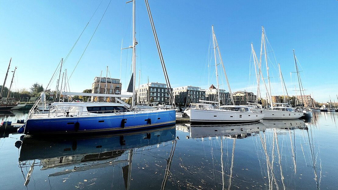 Three Moody yachts sit at anchor in harbor with mirror reflection in the water