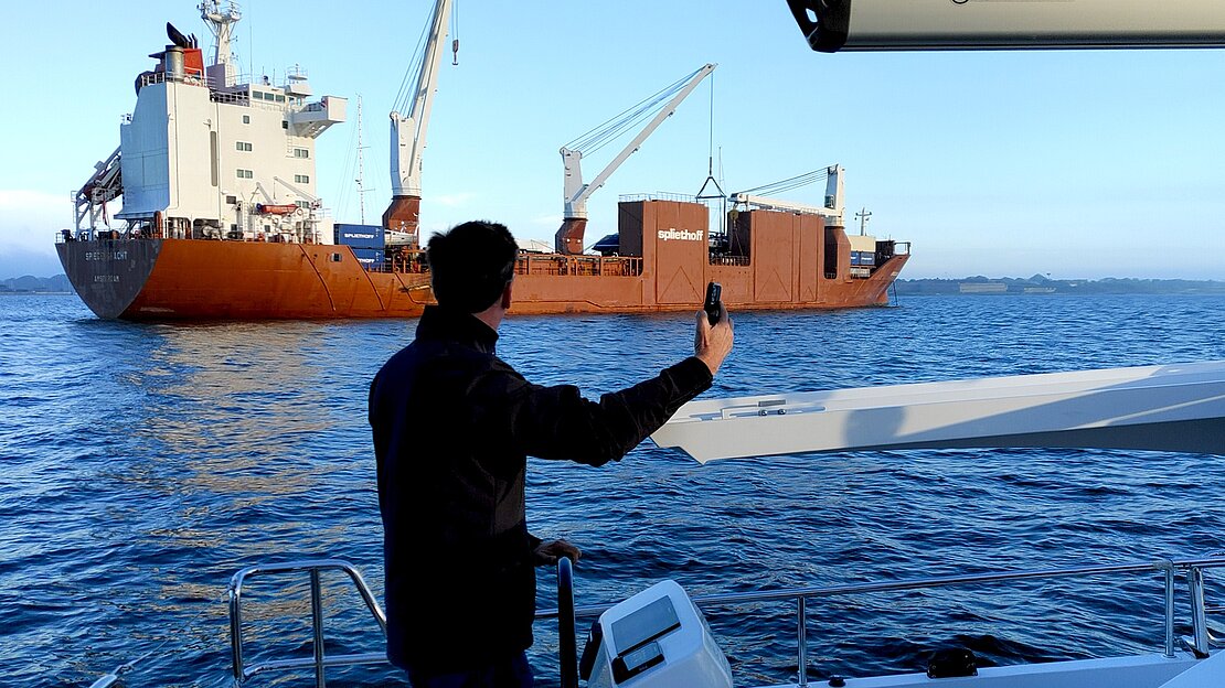 Yachtkapitän winkt dem Frachtschiff, das die neue Yacht geliefert hat, zum Abschied