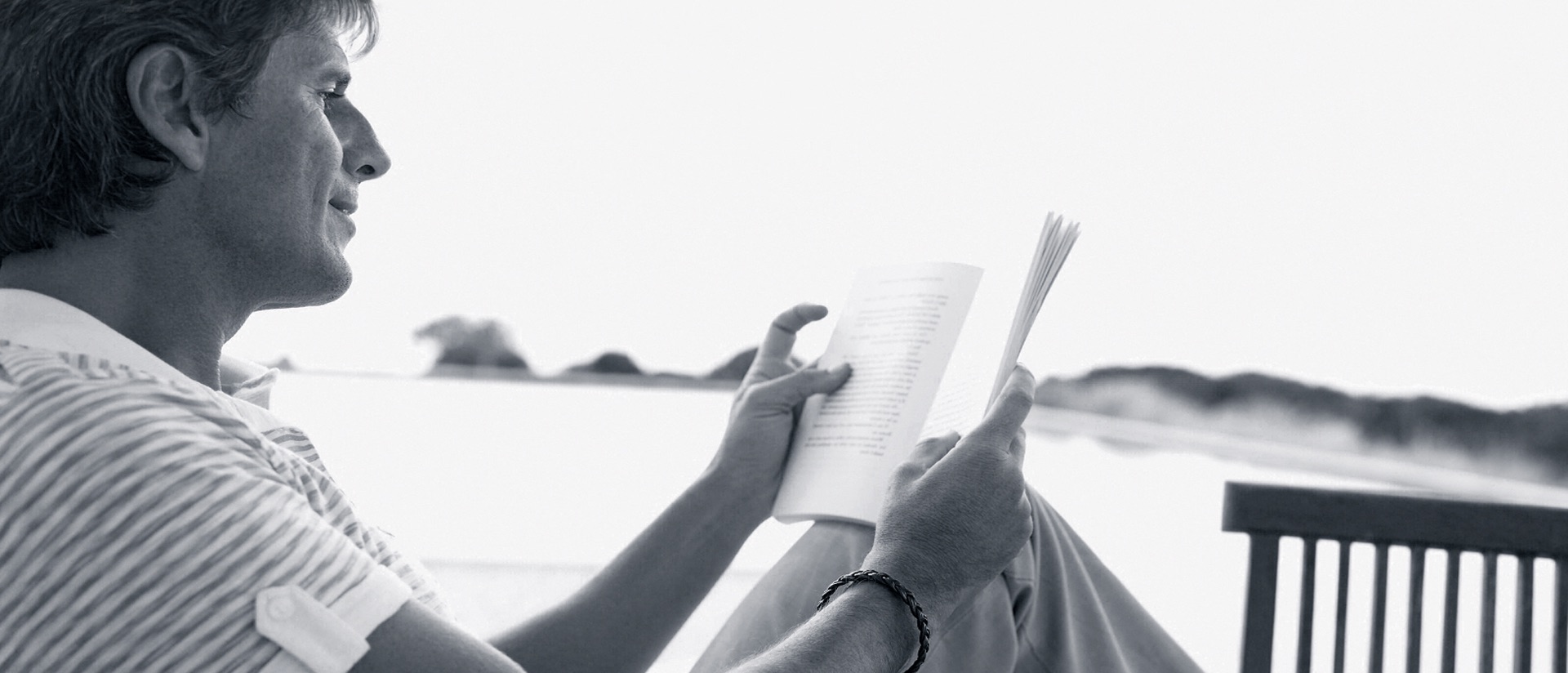 Moody Philosophy, black and white photograph, man reads book at beach